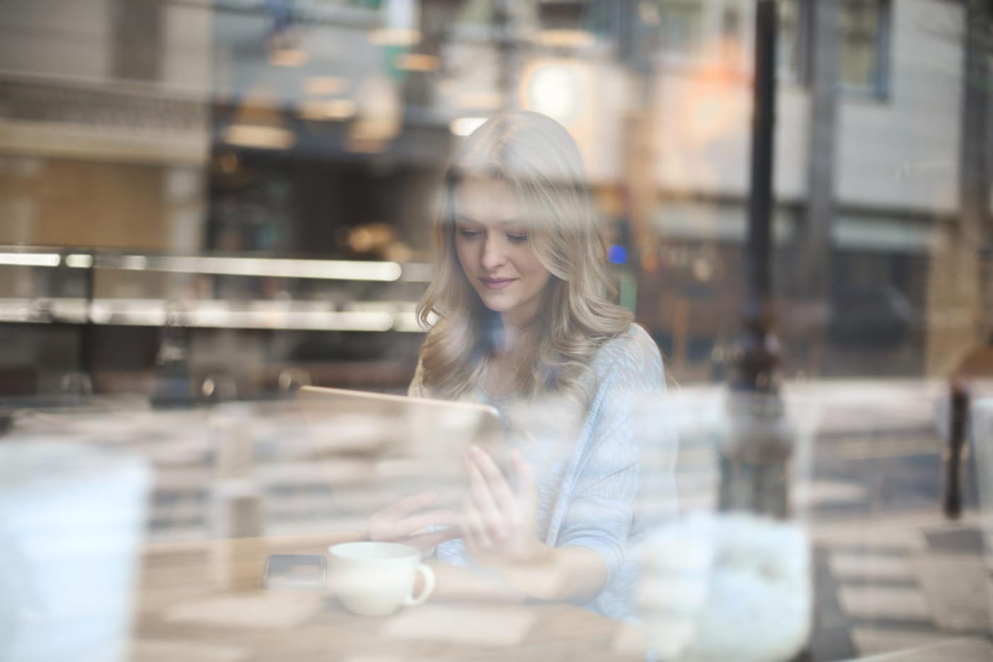 Profesional trabajando en una cafetería, vista a través del cristal