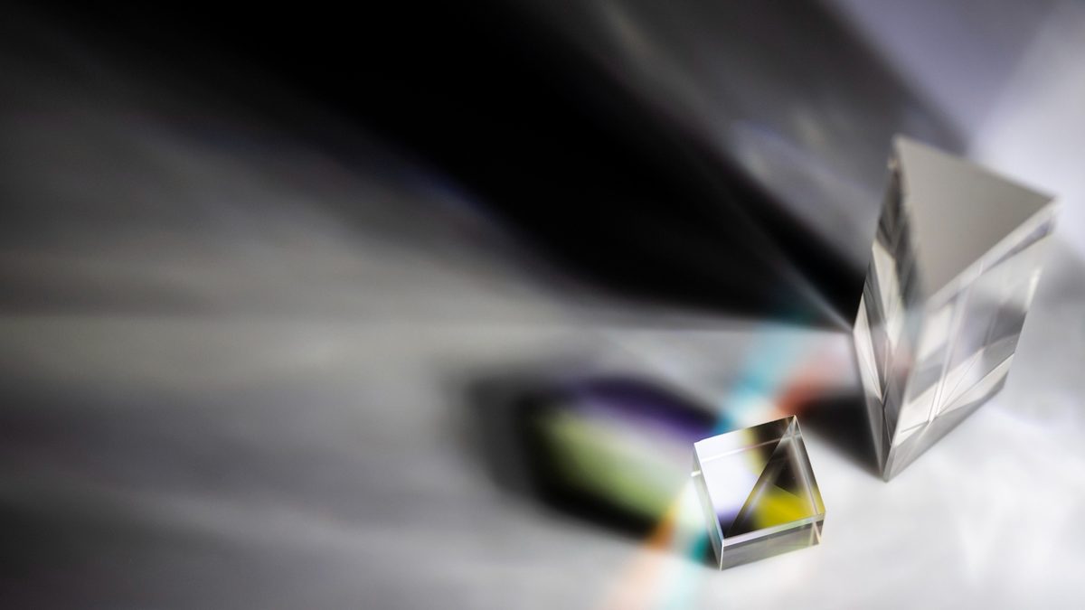 Prismas de cristal dispersando la luz en distintos colores sobre un fondo oscuro, metáfora de una misma esencia con formas distintas